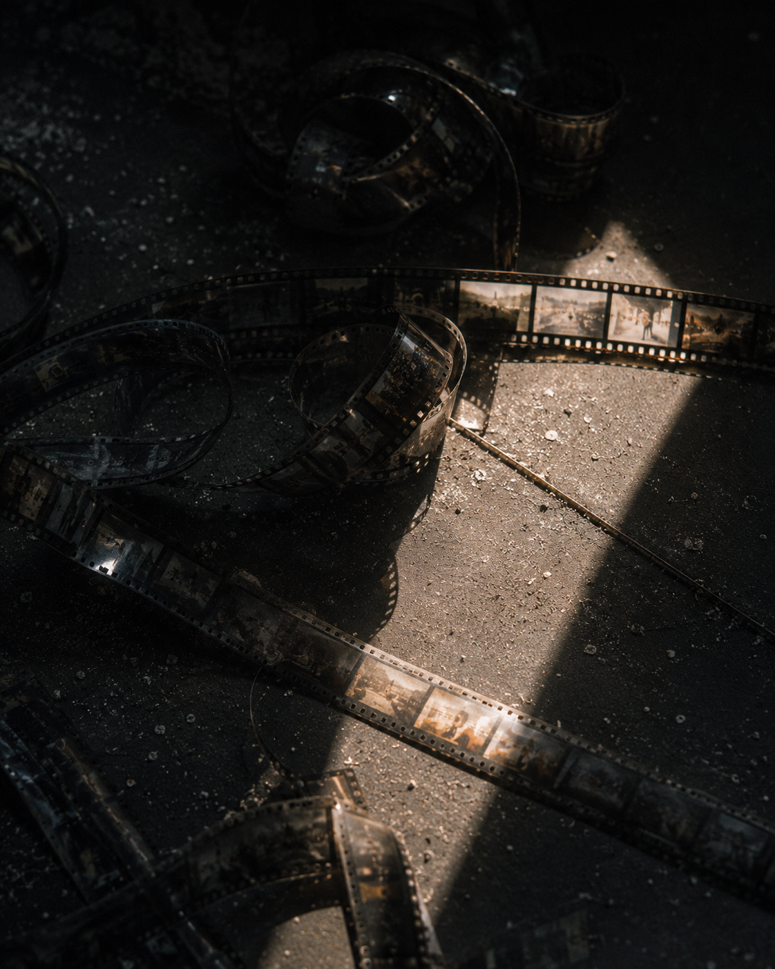Strands of film lying on a dusty cutting room floor in a beam of light